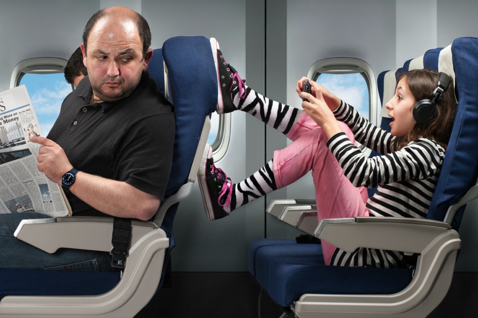 child kicking mans seat on plane