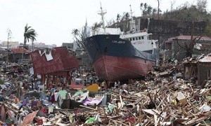 Super typhoon Haiyan: survivors walk past a ship that lies on top of damaged homes