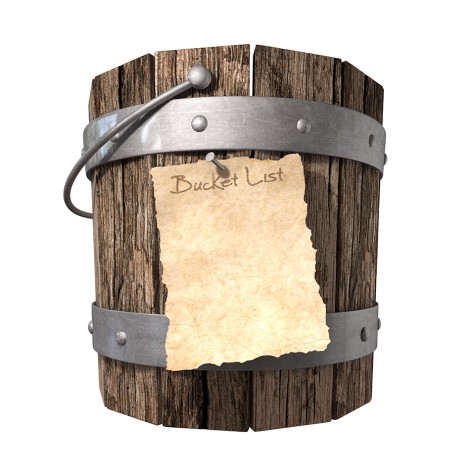 A vintage wooden bucket with metal ring supports and a handle and a aged paper attached to the front that reads bucket list on an isolated background