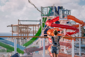 Sint Maarten, Netherlands Antilles - January 5, 2015: A young woman leaning on the deck railing and looking over the onboard water park of Norwegian Cruise Line ship Getaway while sailing near Sint Maarten at Caribbean Sea.