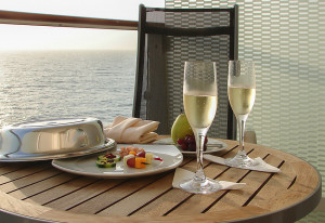Luxury snacks with Champagne glasses: appetizers and fruit on cruise ship balcony.