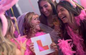Bride having fun with her friends at her bachelorette party and holding a learning sign