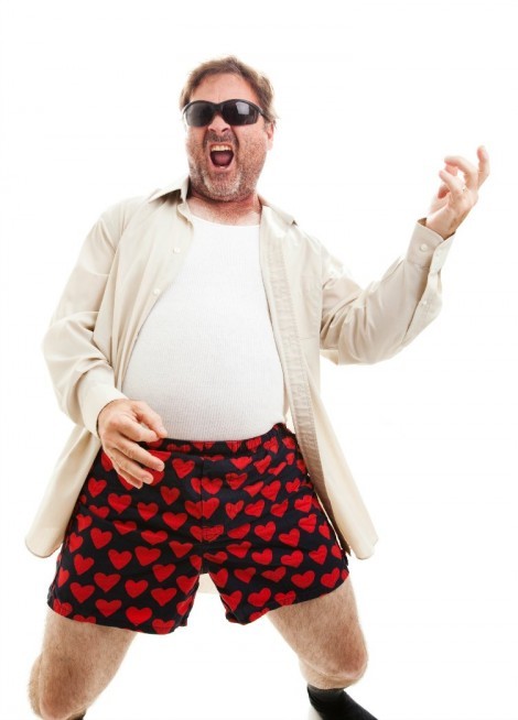 Middle aged man playing air guitar in his underwear.  Isolated on white.