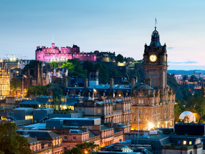Looking across the city of Edinburgh from Calton Hill at dusk. The Balmoral Hotel and an illuminated Edinburgh Castle can be seen.