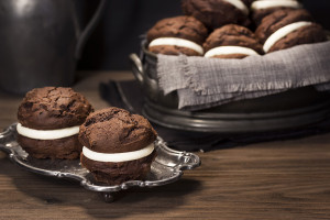 Freshly baked Whoopie (Whoopee) Pies or Moon Pies. Made with cream cheese frosting sandwiched between two layers of chocolate cake. Whoopie Pies are an American dessert that - depending on the story you read - originated in either Pennsylvania or Maine.