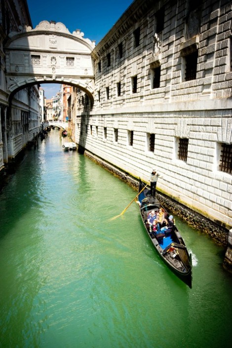 Venice, Italy - April 11, 2015: A couple in a gondola moving down a small Venice canal beside the Doge.s palace. The canal is Rio de Palazzo o de Canonica.