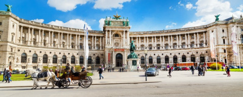 Vienna, Austria - April 3, 2015: Hofburg palace and panoramic square view, people walking and fiaker with white horses in Vienna, Austria
